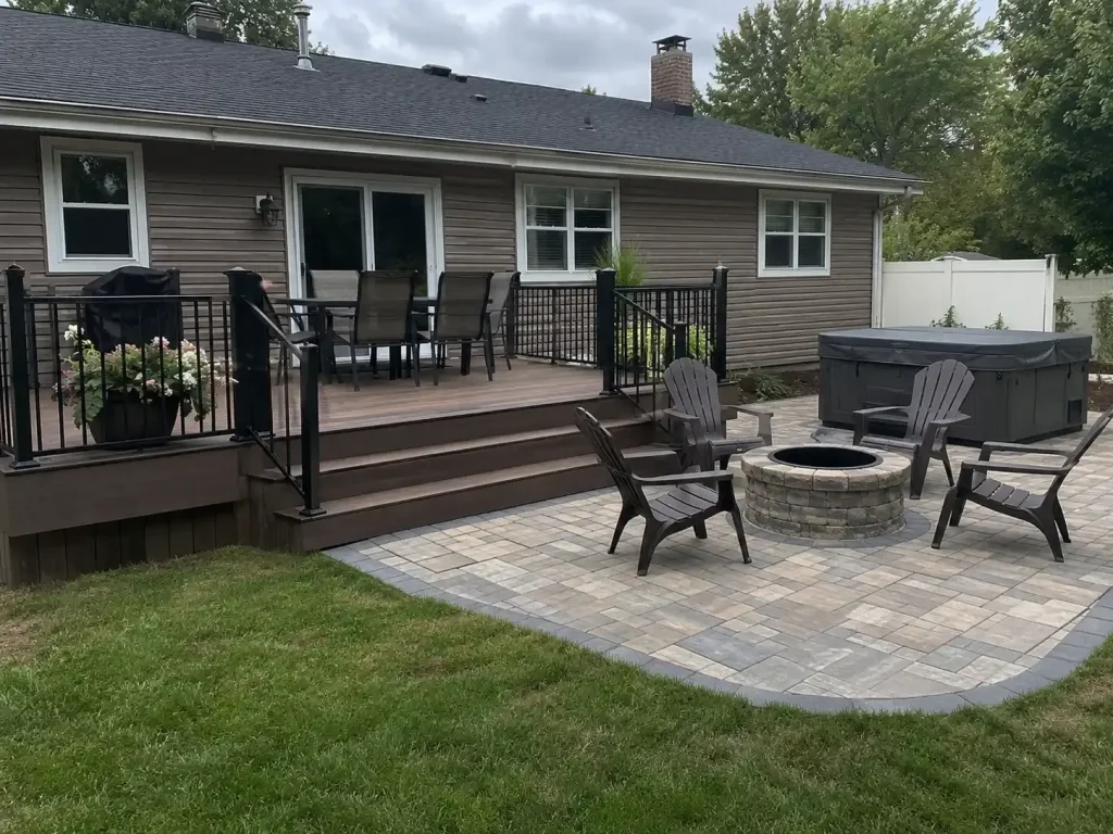 Paver patio with a circular fire pit, Adirondack chairs, and a covered hot tub beside deck steps.
